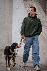 Hundebesitzer beim Spaziergang mit Hund und dem COFFE & DOGS Hoodie in Grün