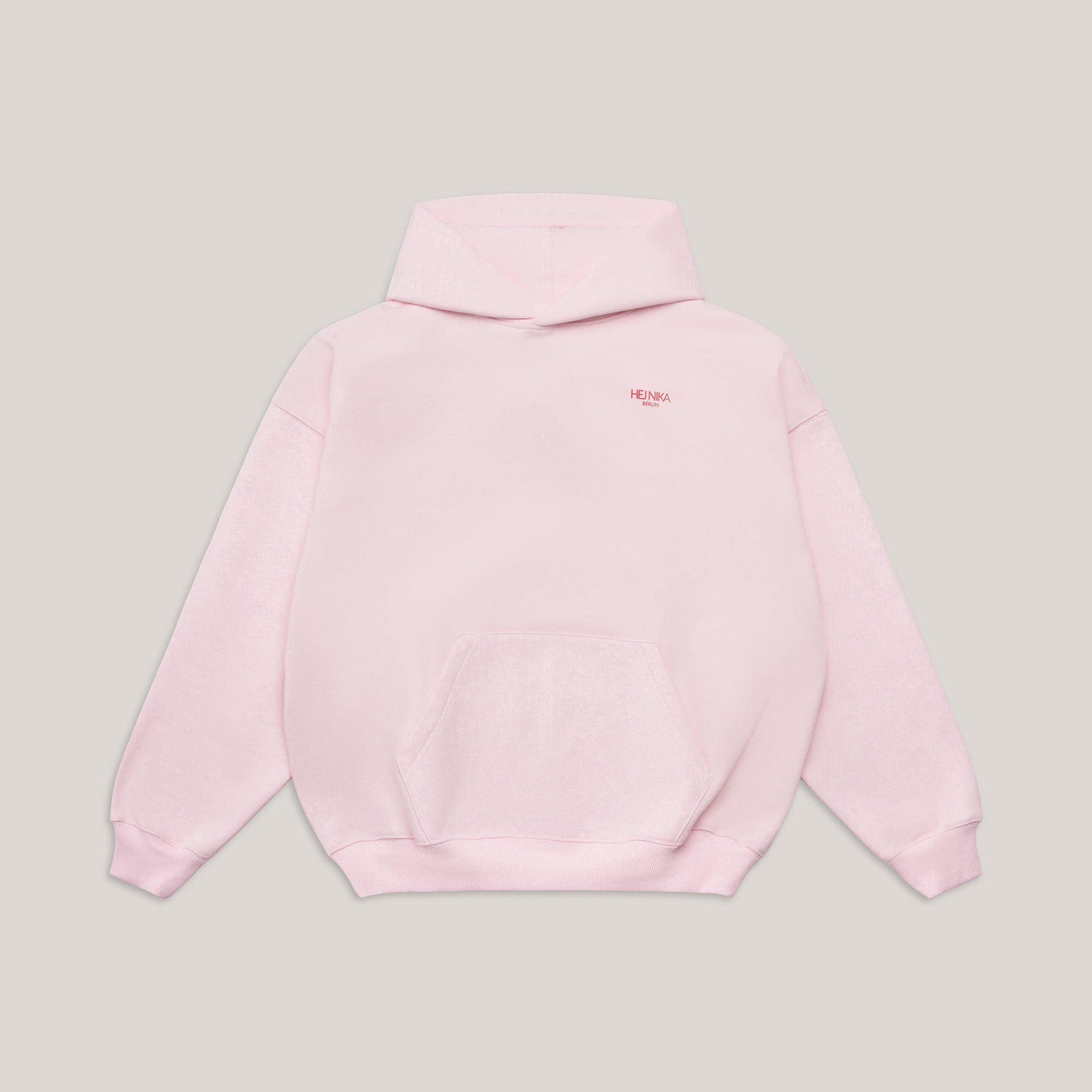 Vorderansicht des Oversized Hoodies in Rosa mit kleinem roten Hej Nika Logo auf der Brust und Kängurutasche.