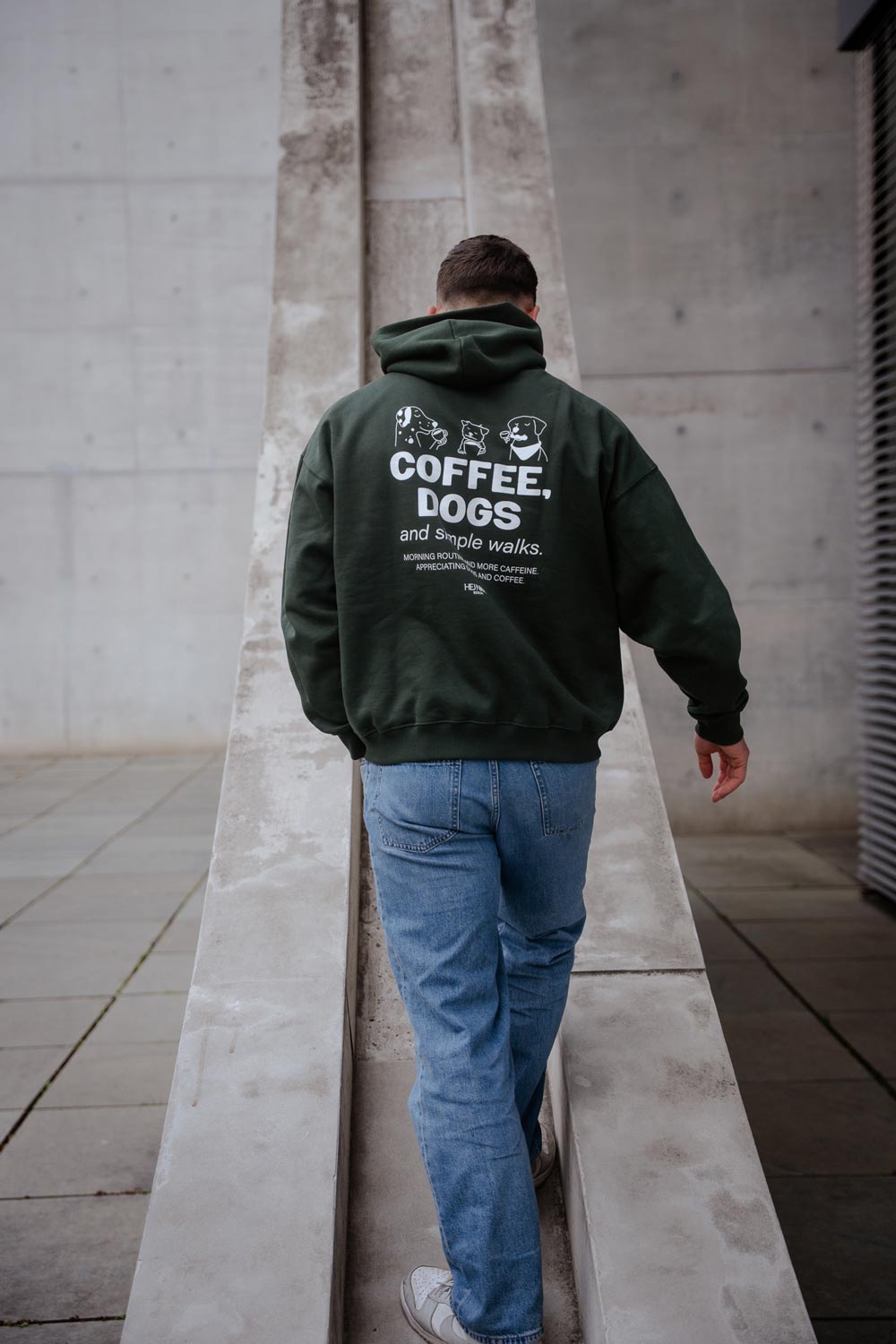 Hundebesitzer:in trägt den grünen COFFEE & DOGS Hoodie beim Spaziergang mit Hund – nachhaltige Mode von Hej Nika