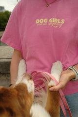 Nahaufnahme einer Frau im pinken Dog Girls T-Shirt, die einen braun-weißen Hund begrüßt.