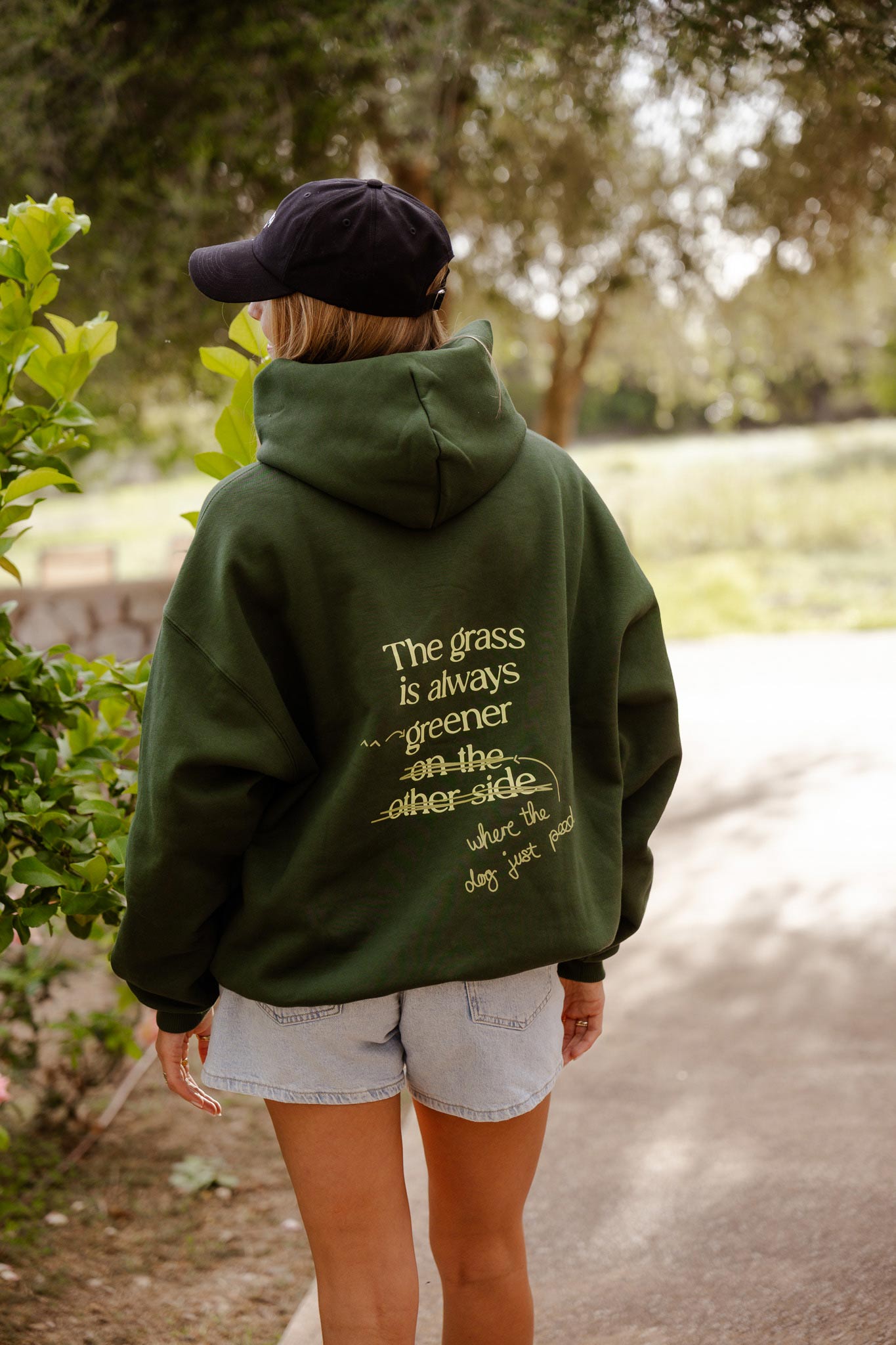 Hundebesitzer:in trägt den grünen Grass is Greener Hoodie von Hej Nika beim Spaziergang – nachhaltige Mode für Hundemenschen