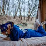 Hundebesitzerin entspannt mit der blauen Jogginghose für Hundebesitzer auf dem Sofa und genießt den Abend. 