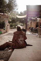 Hundebesitzer trägt Unisex Sweatjacke in Braun beim gemeinsamen entspannen mit Hund im garten.