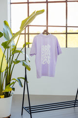 T-Shirt für Hundebesitzer "Girls Just Wanna" in einem pastell Lavendelton an einer Kleiderstange beim Shooting – 100% Bio-Baumwolle - nachhaltig, stylisch & pflegeleicht – Hej Nika