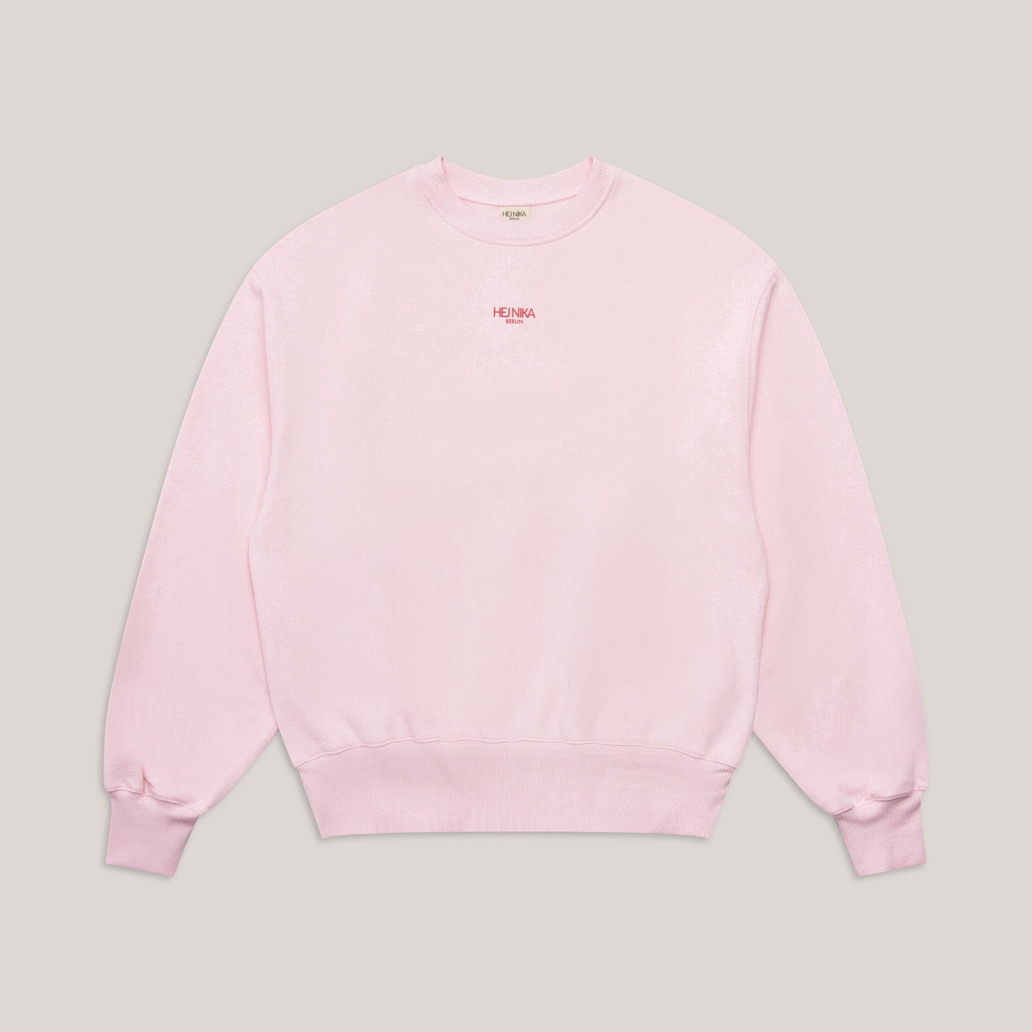 Vorderansicht des rosa Rundhals-Sweaters (Crewneck) mit kleinem roten Hej Nika Logo, oversized geschnitten.
